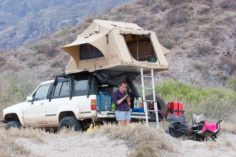 Woman reading emails from the back of her vehicle.