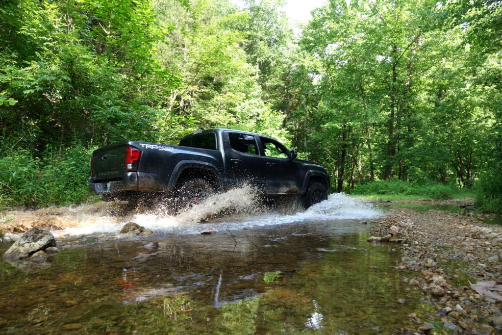 A side view of a Tacoma in a shallow water crossing.