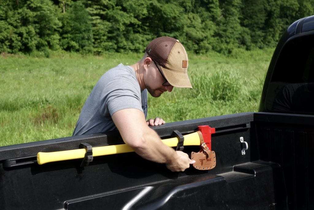 Man securing an axe inside a truck bed.