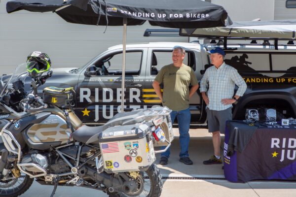 Rider Justice talking to motorcyclist at display at event with BMW GS