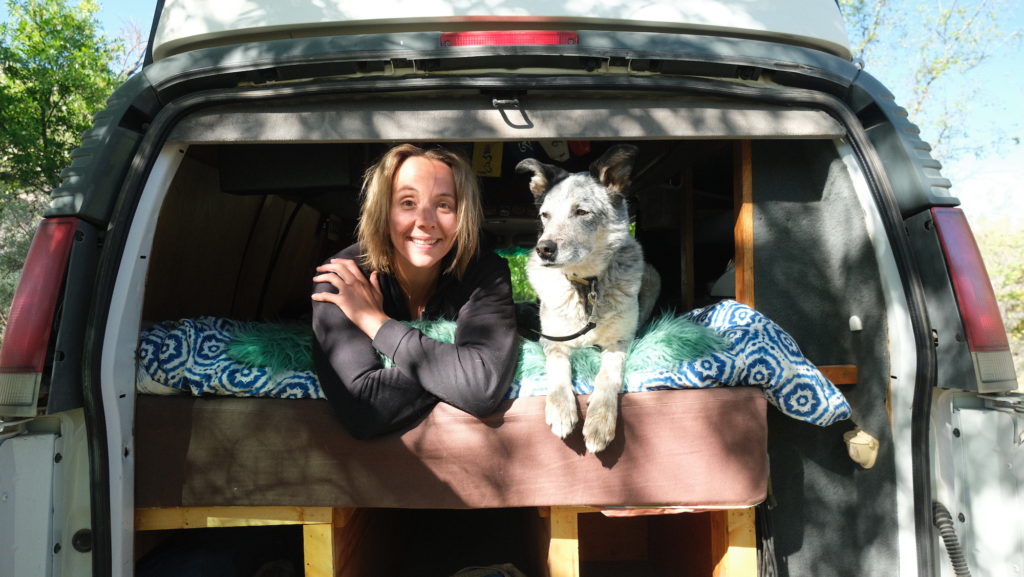 Woman and dog lounge together in the back of a van