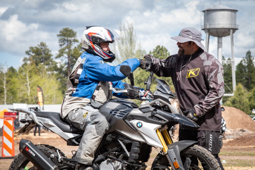 Adventure motorcycle coach fist bumps student on BMW GS