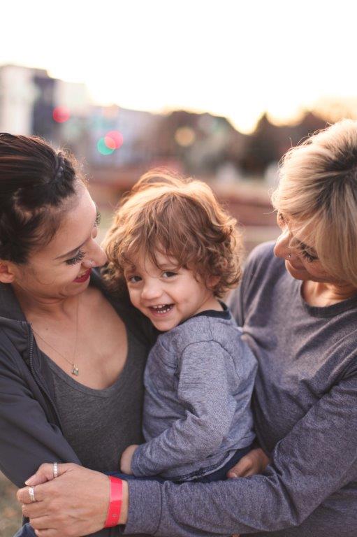 Image shows a family hug with a smiling child in the center. 