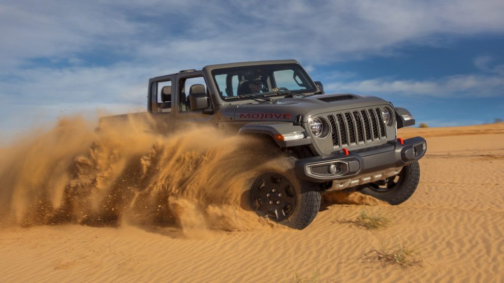 Jeep Gladiator throwing sand as it turns through a dune.