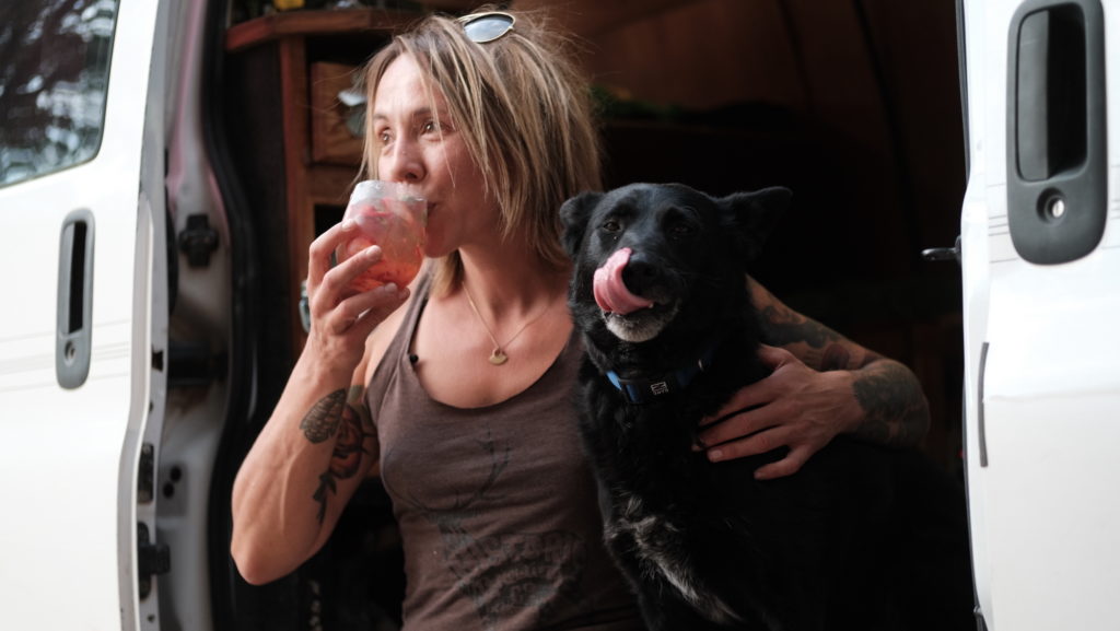 Woman hugs dog while she takes a sip of a cocktail