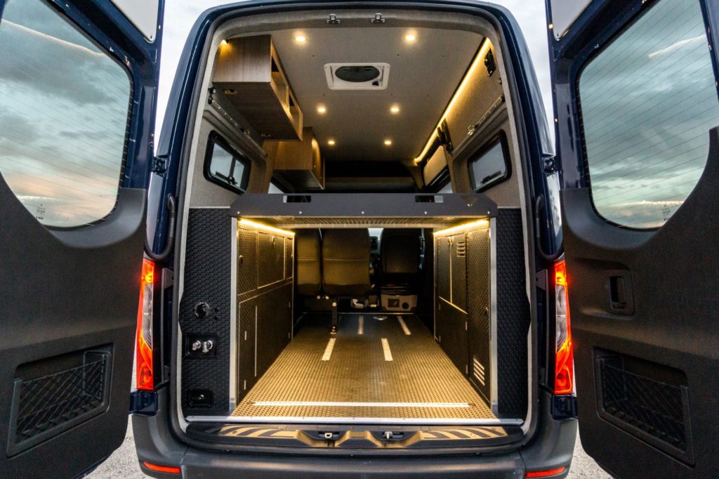 Shows the open rear doors of a customized Sprinter van.