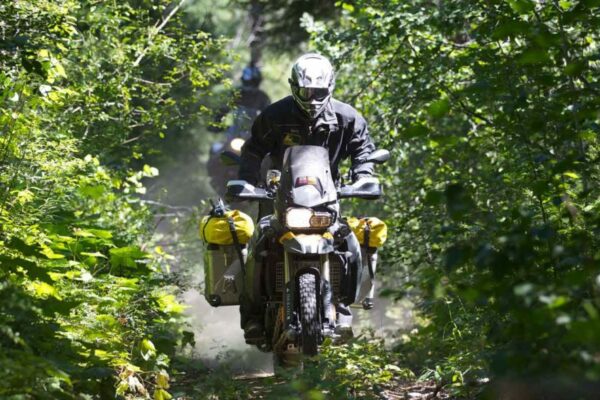 Adventure motorcycle going through a tree-covered trail