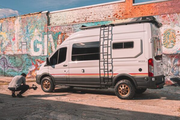 Storyteller Overland Ford Transit van in front of a wall with grafitti