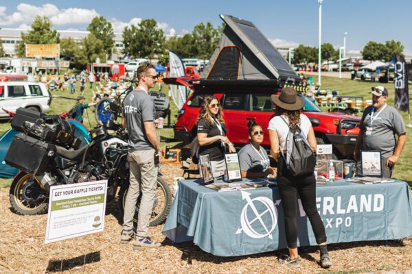 Overland Expo staff stand in front of their Ultimate Overland Builds 2021 booth