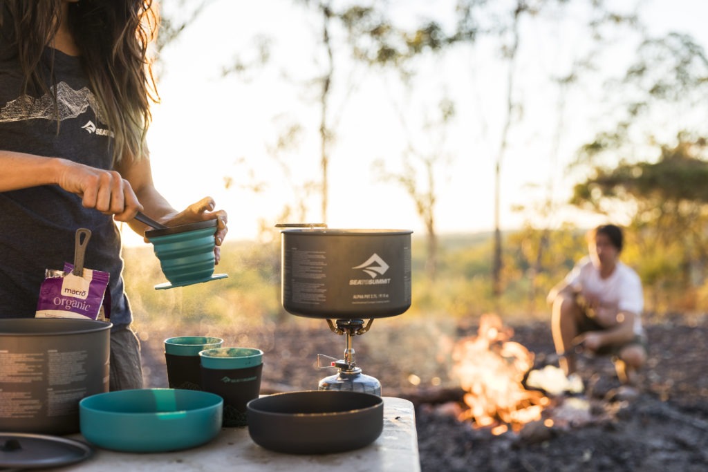 Camping cooking scene with fire in the background