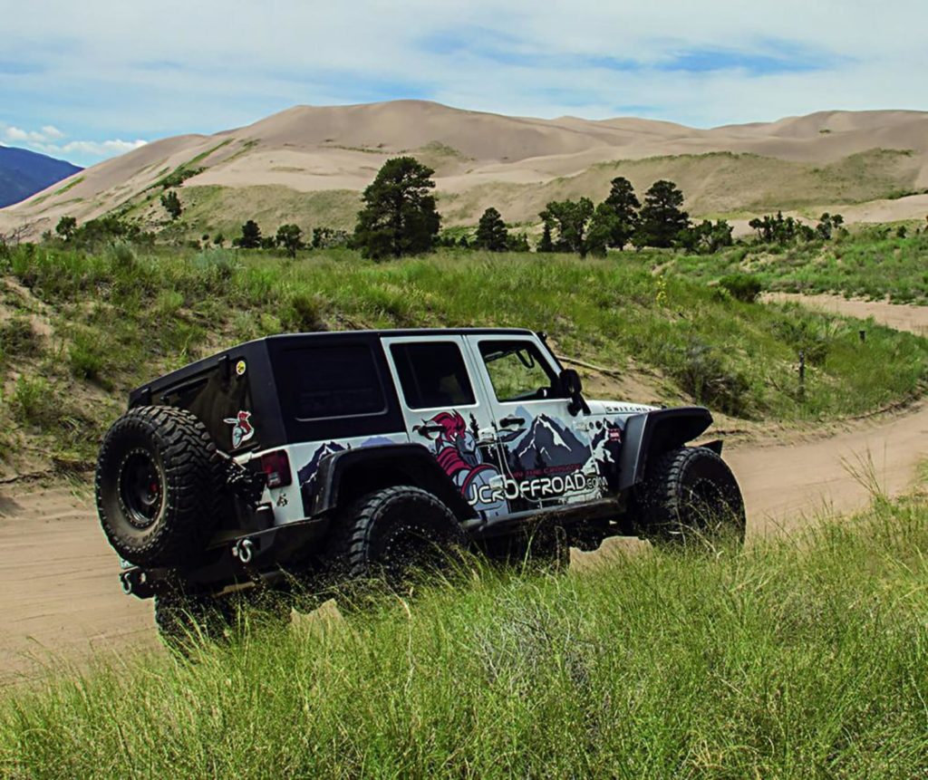 Jeep with sand dunes in the background.