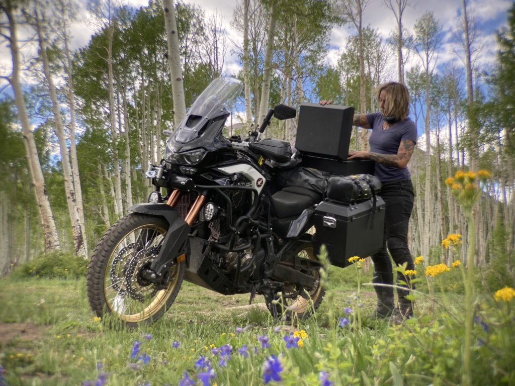 Woman motorcyclist opens Jesse Luggage panniers at campsite 