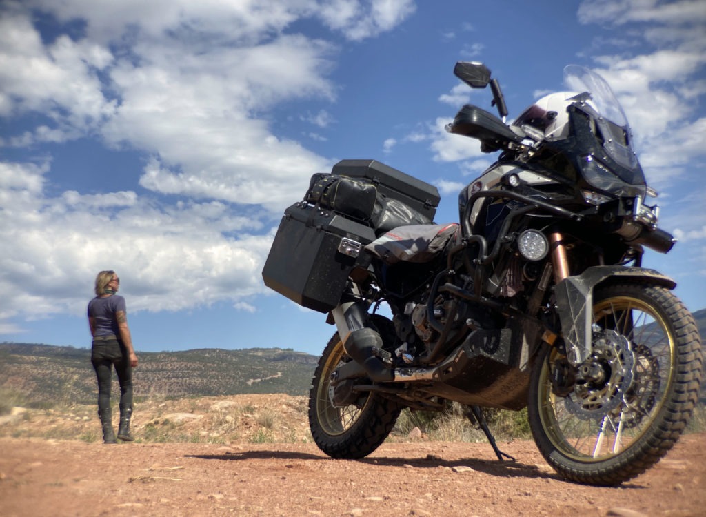 Honda Africa Twin parked in Utah desert with woman motorcyclist in the background