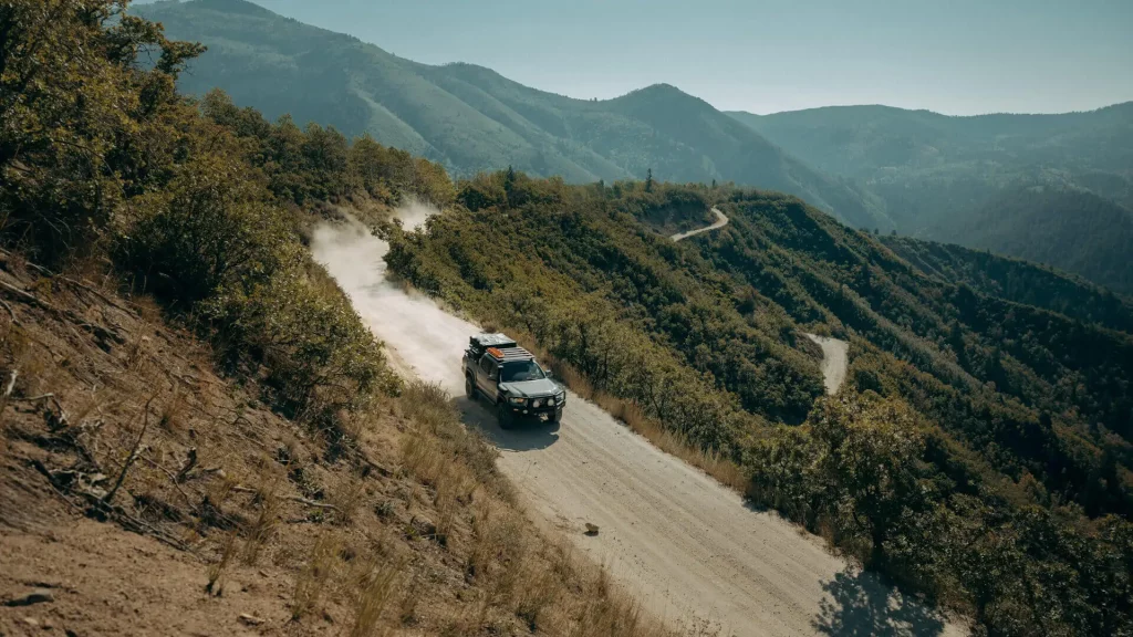 Toyota Tacoma driving down a forest service road in the mountains.