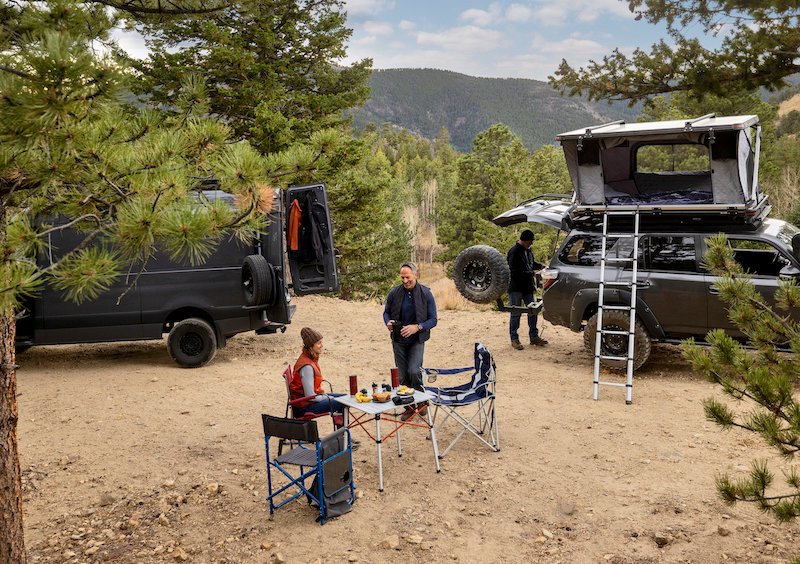 Two people at a remote backcountry campsite in their overland vehicles.