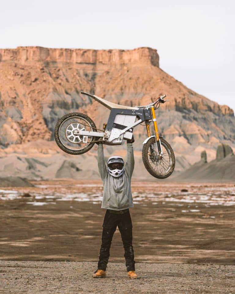 RIDER HOLDS UP CAKE E-BIKE IN DESERT LIGHTWEIGHT ELECTRIC BICYCLE