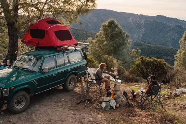 People at camp overlooking a forest at the top of a mountain trail.