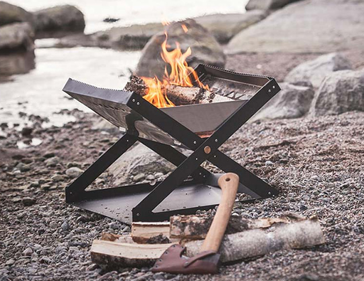 A Primus Kamoto Open Fire Pit on the beach with a fire burning.