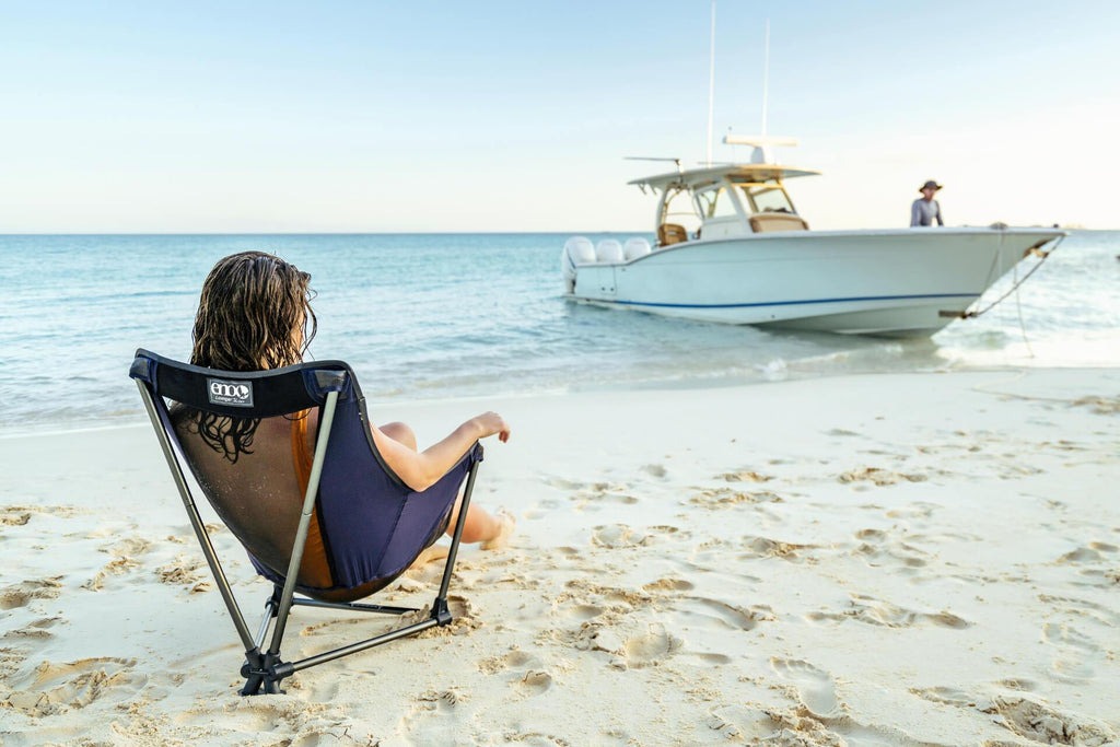 Woman sitting on the beach in an (ENO) Lounger SL Chair.