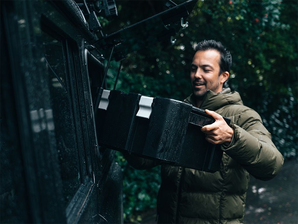 Man loading his vehicle in the rain with a Wolf Pack Pro box.