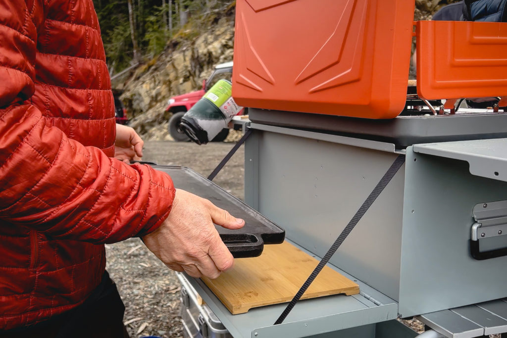 The hidden vertical panel of the Green Goat Outdoors Camp Kitchen stores a griddle and cutting board.