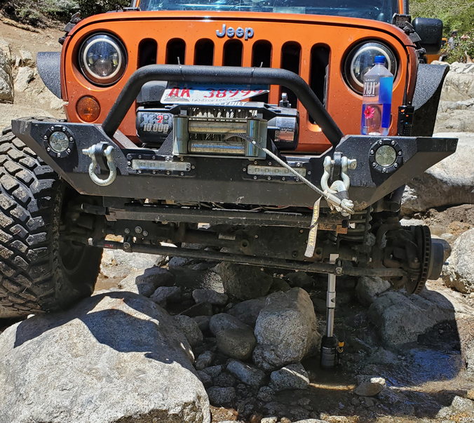 A Jeep lifted to repair a tire using a Safe Jack General bottle jack