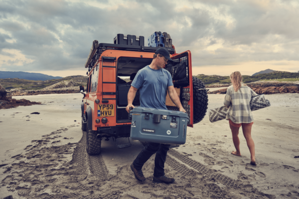 Man unloading a cooler from a Defender.