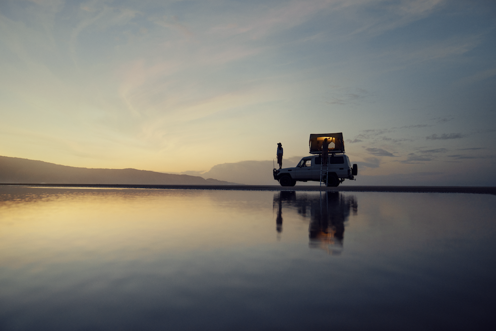 Truck with rooftop tent next to a lake.