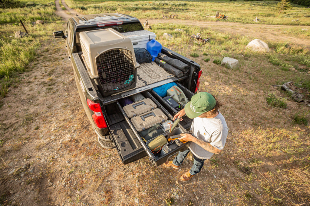 Man accessing DECKED Drawer System with a loaded truck bed utilizing the DECKED Traction Mat by SeaDek.