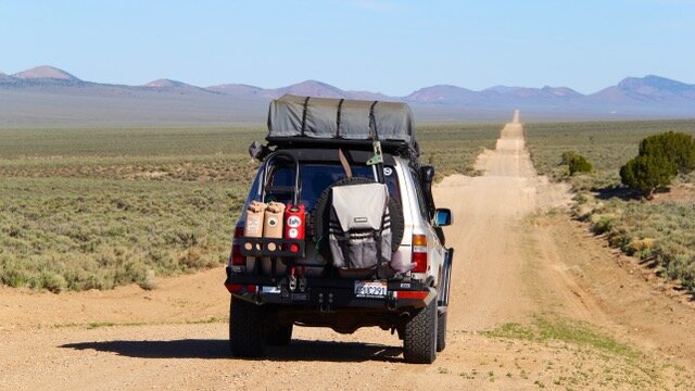 Land Cruiser driving down a dirt road in the desert.