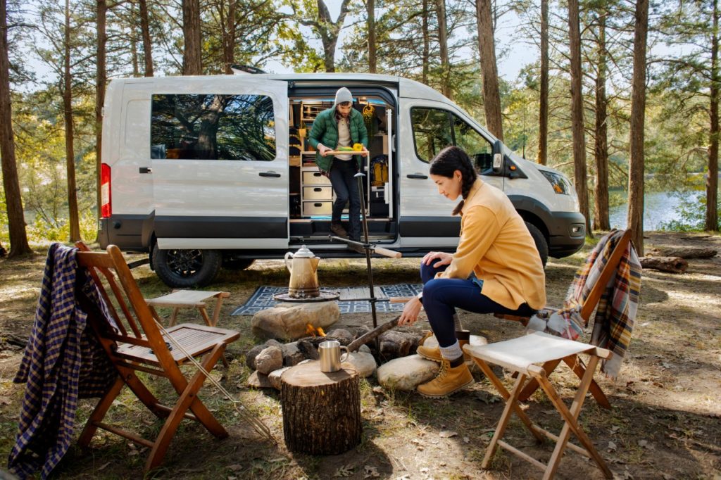 People enjoying the outdoors while staying in a Ford Transit Trail van.