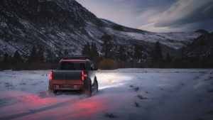 Canoo Pickup driving through snow in the mountains.